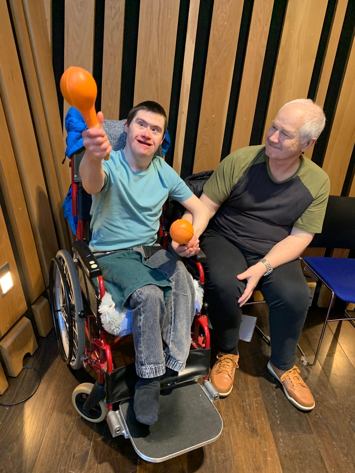 Beneficiary playing maracas with a Sunbeams musician