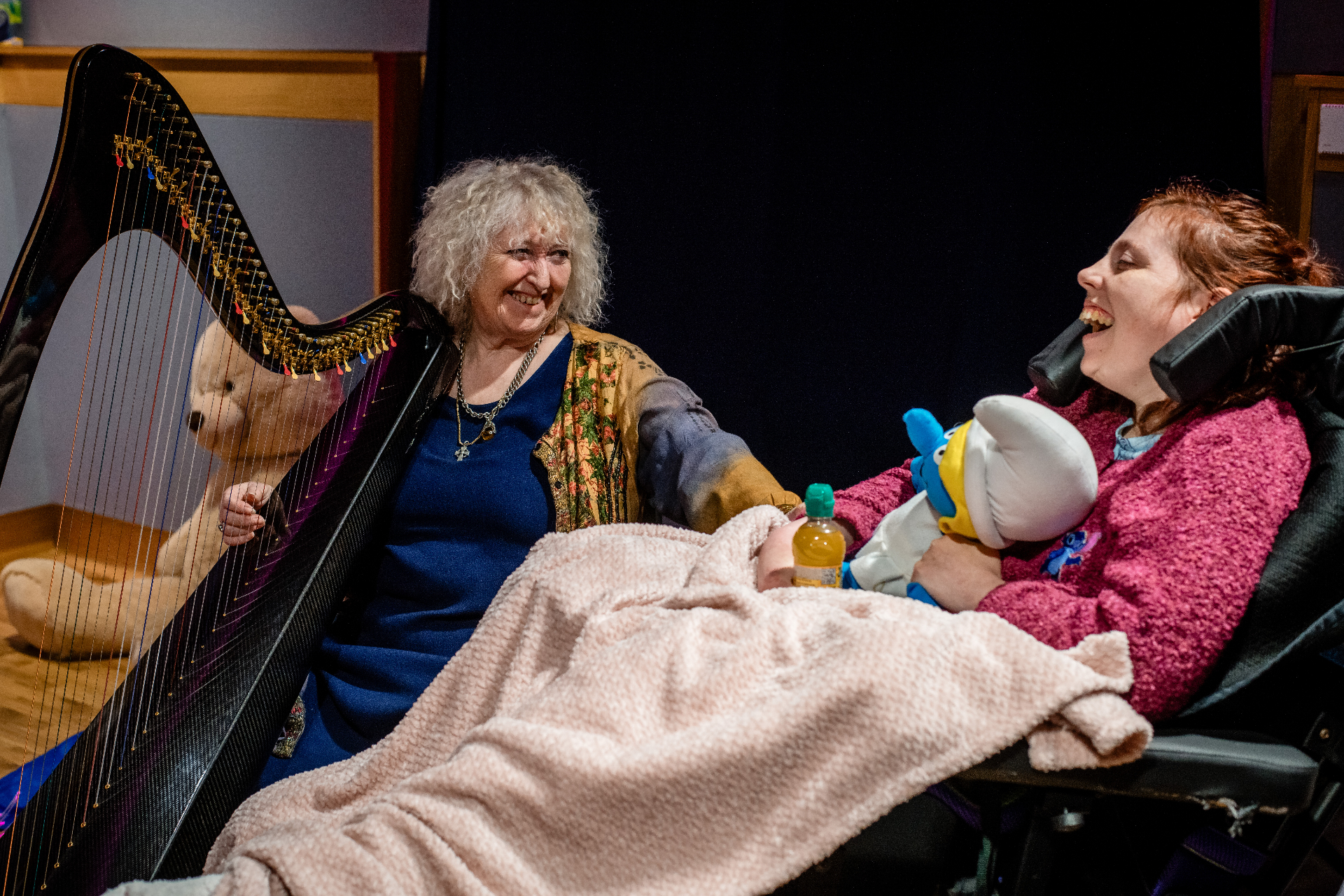 Annie Mawson playing harp with a beneficiary